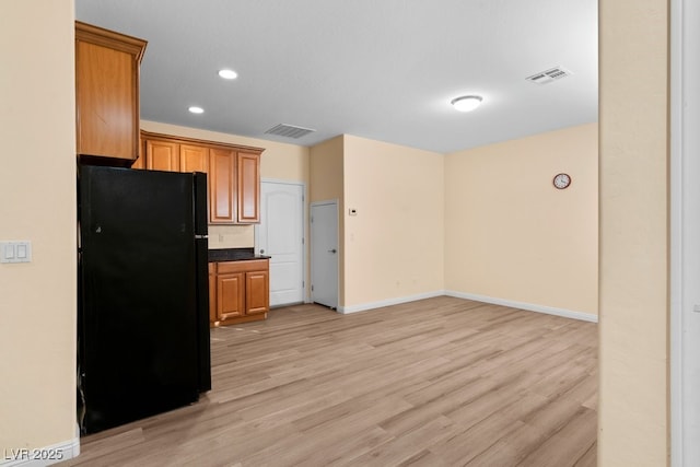 kitchen with black refrigerator and light hardwood / wood-style flooring