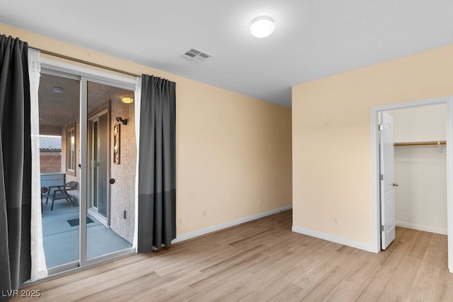 unfurnished bedroom with a walk in closet, light wood-type flooring, and a closet