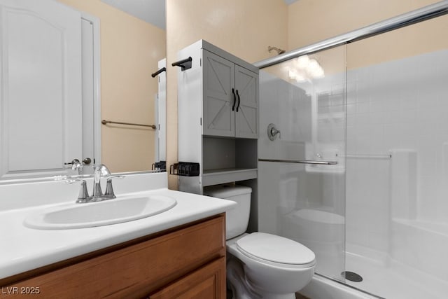 bathroom featuring vanity, a shower with shower door, and toilet