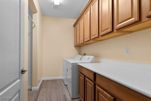 washroom featuring cabinets, light hardwood / wood-style floors, and washer and clothes dryer