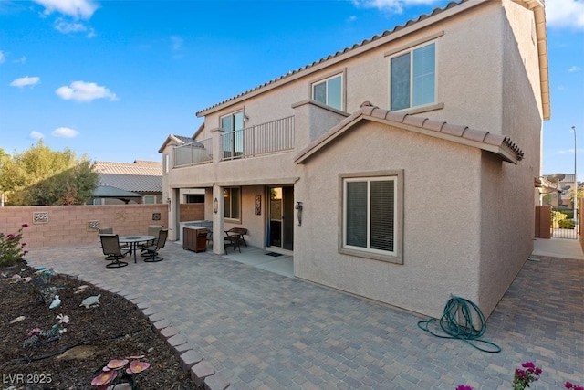 rear view of property featuring a balcony, a hot tub, and a patio area