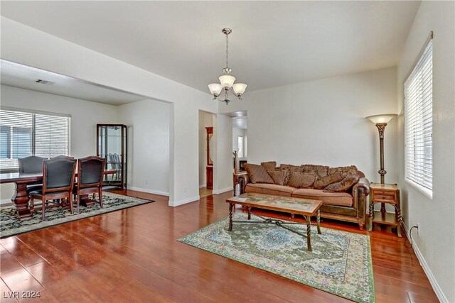 living room featuring a healthy amount of sunlight, dark hardwood / wood-style flooring, and an inviting chandelier