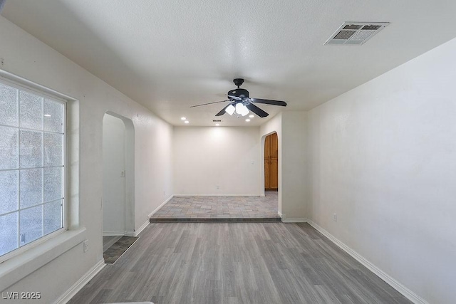 spare room featuring ceiling fan, plenty of natural light, wood-type flooring, and a textured ceiling