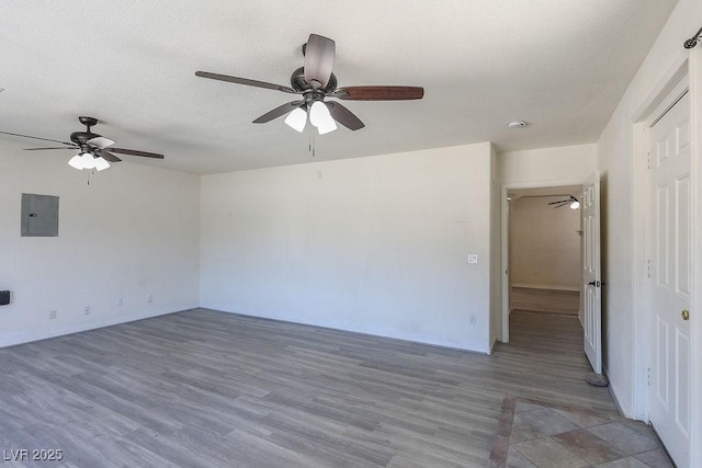 spare room featuring electric panel, hardwood / wood-style floors, and a textured ceiling