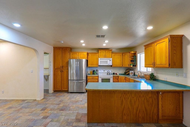 kitchen featuring kitchen peninsula, white appliances, and sink