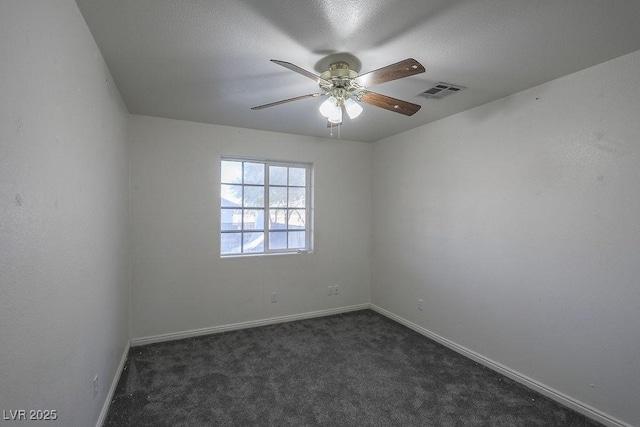 spare room featuring dark carpet and ceiling fan