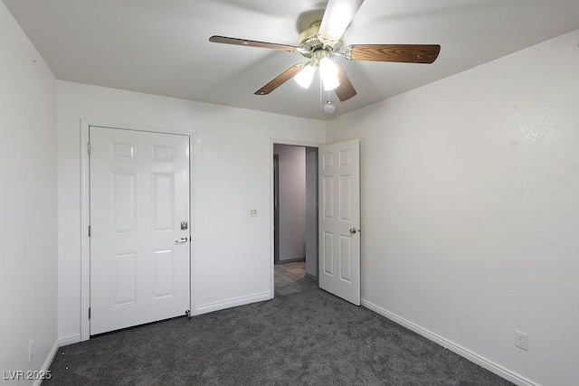 unfurnished bedroom with dark colored carpet and ceiling fan