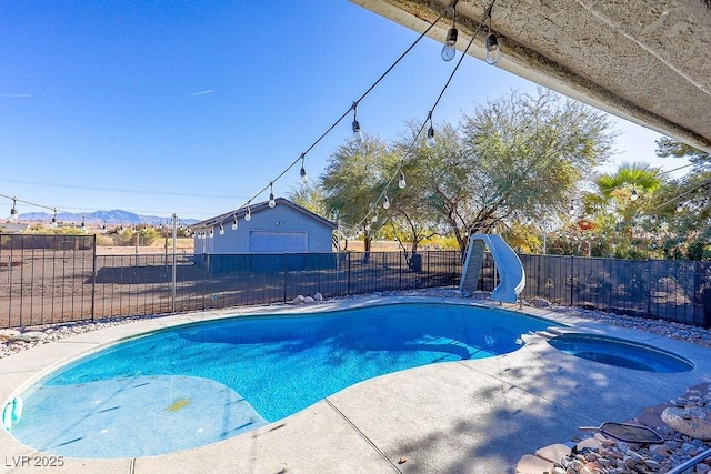 view of swimming pool with a mountain view, an outbuilding, a water slide, and an in ground hot tub