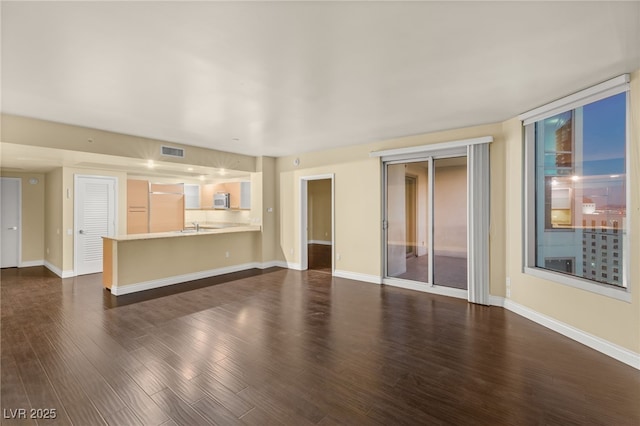 unfurnished living room with dark wood-type flooring and a wall of windows