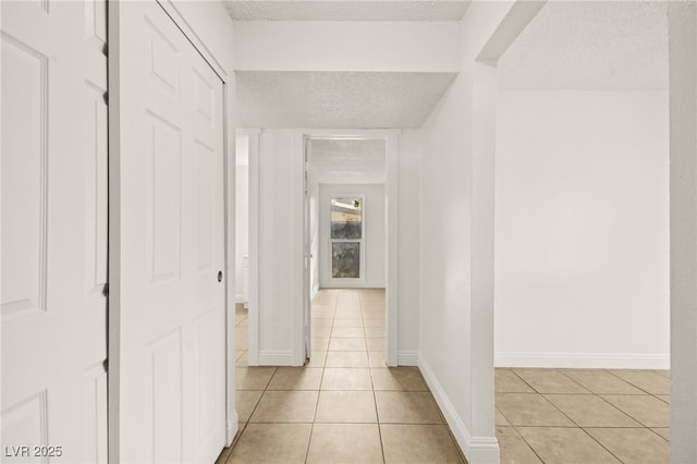 corridor with light tile patterned floors and a textured ceiling