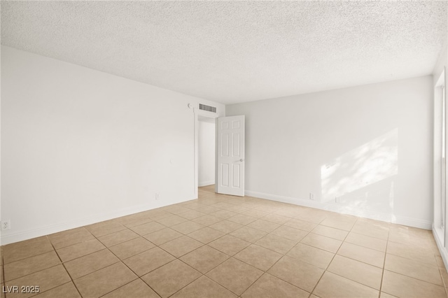 unfurnished room with light tile patterned floors and a textured ceiling