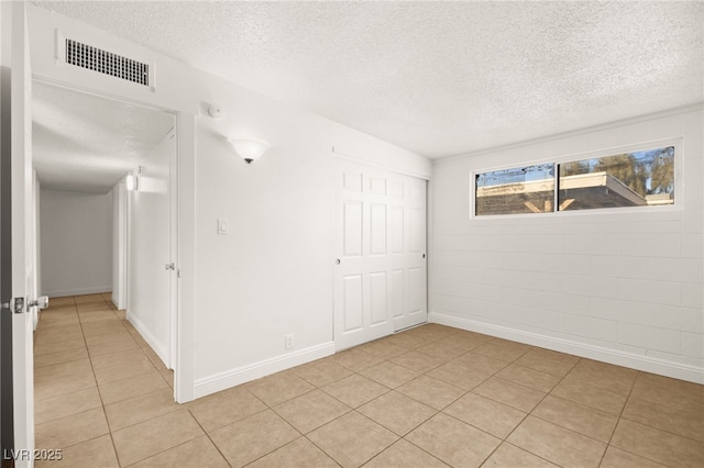 empty room featuring light tile patterned floors and a textured ceiling