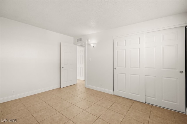 unfurnished bedroom with light tile patterned floors, a textured ceiling, and a closet