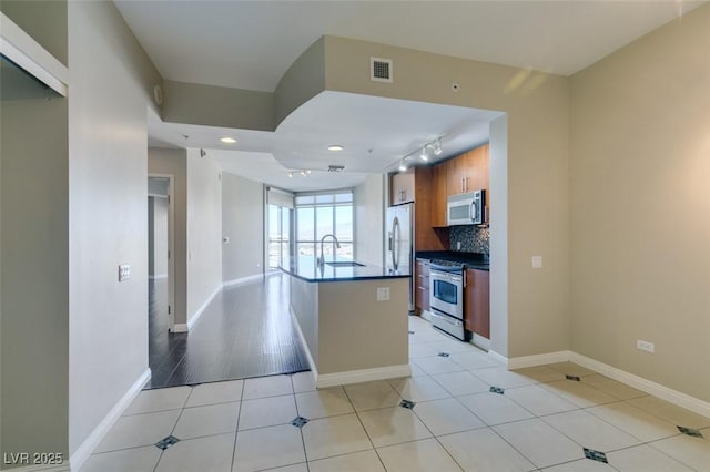 kitchen with track lighting, sink, light tile patterned floors, tasteful backsplash, and stainless steel appliances