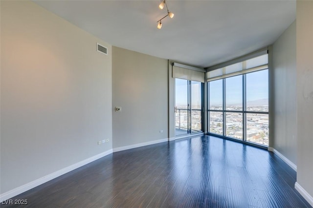 unfurnished room featuring a water view, dark wood-type flooring, and a wall of windows