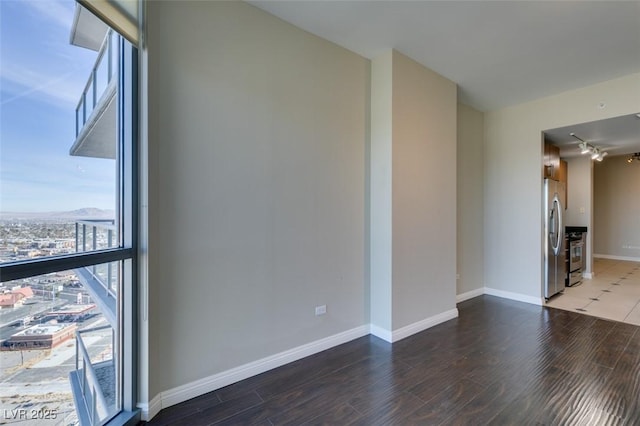 empty room featuring track lighting and dark wood-type flooring