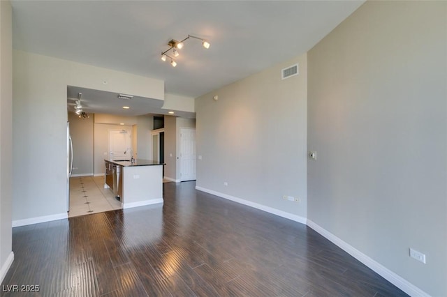 unfurnished living room featuring ceiling fan, dark hardwood / wood-style flooring, and sink