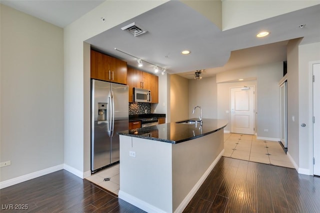 kitchen with light hardwood / wood-style floors, sink, stainless steel appliances, and a kitchen island with sink