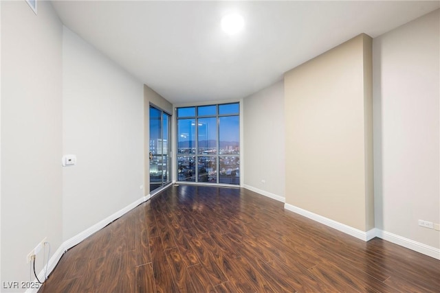 unfurnished room with expansive windows and dark wood-type flooring