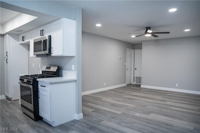 kitchen featuring ceiling fan, white cabinets, stainless steel appliances, and light wood-type flooring