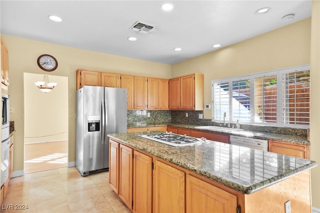 kitchen featuring a center island, white appliances, dark stone counters, sink, and light tile patterned flooring