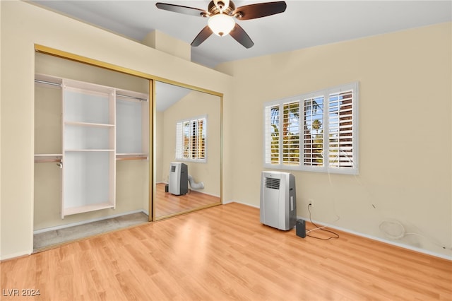 unfurnished bedroom with ceiling fan, a closet, vaulted ceiling, and light wood-type flooring