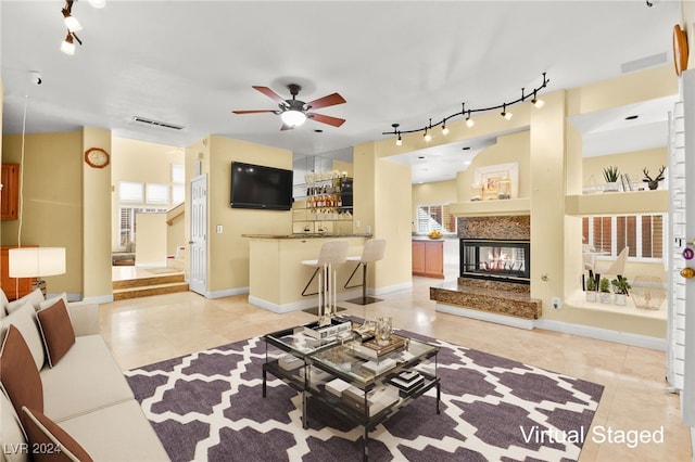 living room featuring ceiling fan, light tile patterned flooring, and a high end fireplace