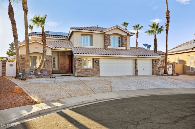 mediterranean / spanish-style house featuring solar panels and a garage