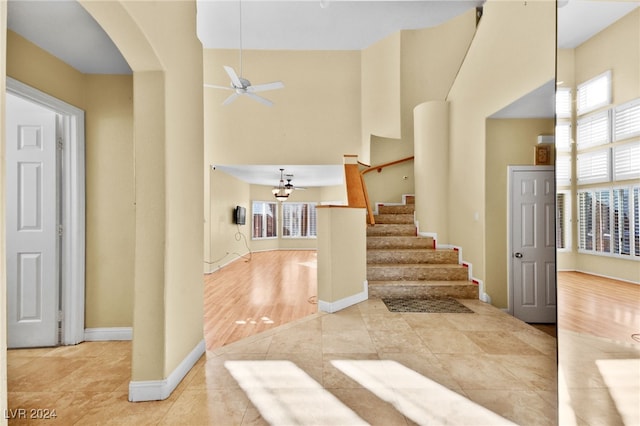 entrance foyer with ceiling fan, light tile patterned floors, and a high ceiling