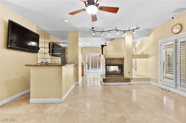 kitchen featuring a multi sided fireplace, kitchen peninsula, light tile patterned flooring, and rail lighting