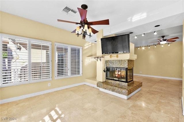 unfurnished living room with ceiling fan and a multi sided fireplace