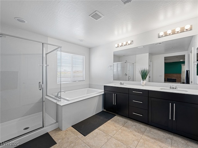 bathroom featuring plus walk in shower, vanity, a textured ceiling, and tile patterned floors