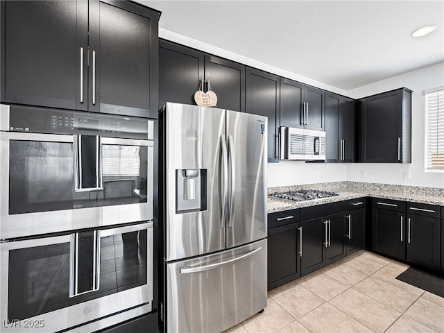 kitchen featuring light stone countertops, light tile patterned floors, and stainless steel appliances