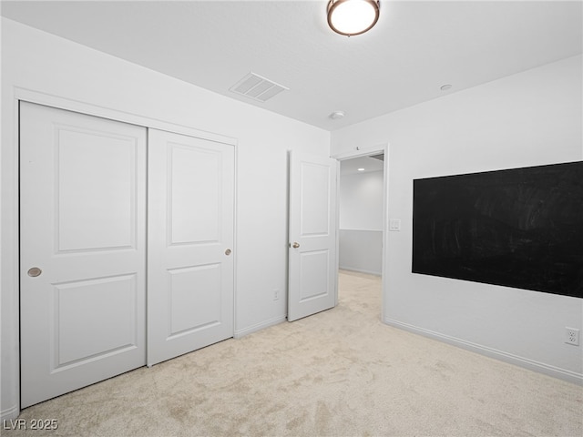 unfurnished bedroom with light colored carpet and a closet