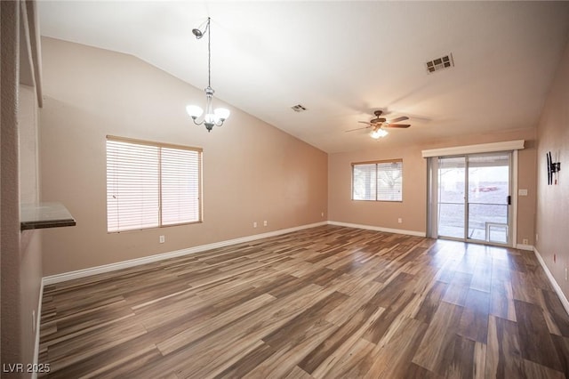 empty room featuring ceiling fan with notable chandelier, dark wood-type flooring, and lofted ceiling