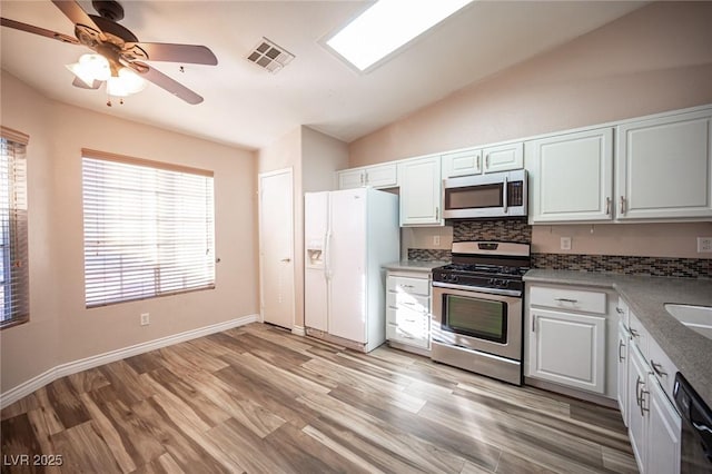 kitchen featuring lofted ceiling, backsplash, light hardwood / wood-style flooring, white cabinetry, and stainless steel appliances