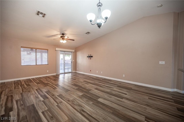 empty room featuring ceiling fan with notable chandelier, dark hardwood / wood-style floors, and vaulted ceiling