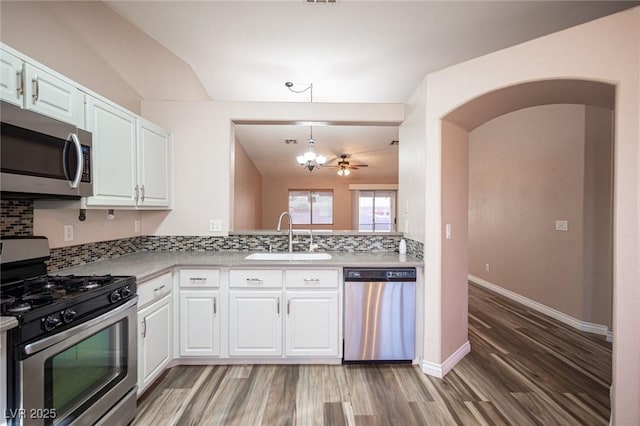 kitchen with white cabinetry, sink, stainless steel appliances, and ceiling fan with notable chandelier