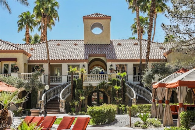 view of front facade with a tile roof, stairs, and stucco siding