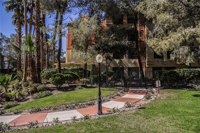 view of community featuring a lawn and fence