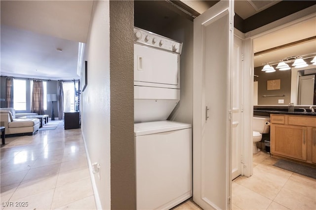 laundry room featuring a sink, laundry area, light tile patterned floors, and stacked washer / dryer