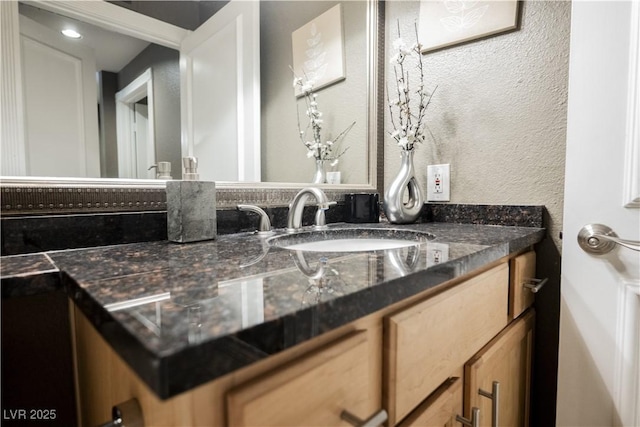 bathroom featuring a textured wall and vanity