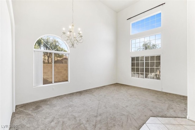 carpeted empty room with a high ceiling and a chandelier