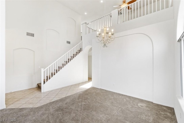 staircase with tile patterned flooring, ceiling fan, and a towering ceiling