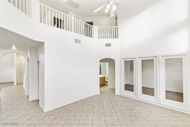 spare room featuring ceiling fan, light tile patterned flooring, and a high ceiling