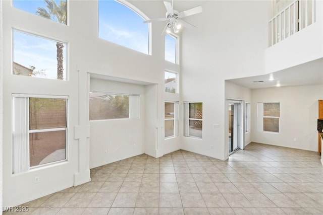 interior space featuring ceiling fan, light tile patterned floors, and a high ceiling