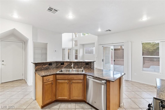 kitchen featuring stainless steel dishwasher, sink, a wealth of natural light, and dark stone counters