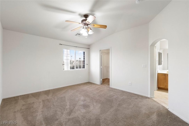 unfurnished bedroom with ceiling fan, light colored carpet, lofted ceiling, and ensuite bathroom