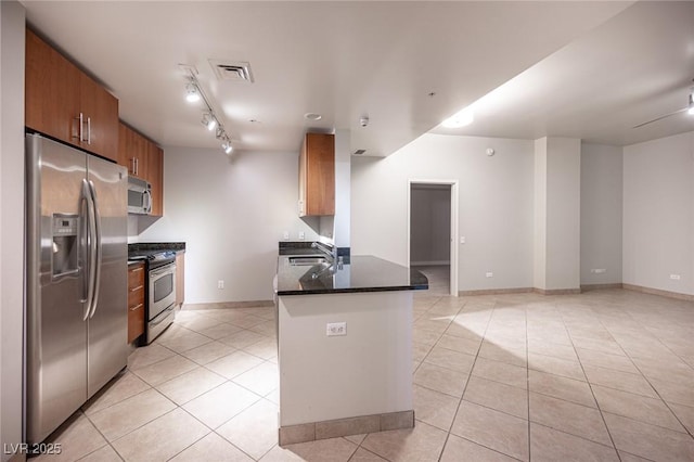 kitchen featuring sink, dark stone countertops, light tile patterned flooring, kitchen peninsula, and stainless steel appliances