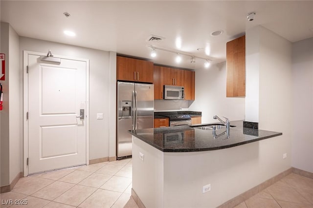 kitchen with sink, stainless steel appliances, kitchen peninsula, dark stone counters, and light tile patterned flooring